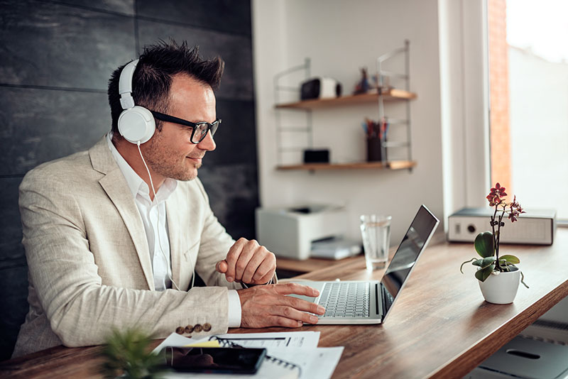 Man with laptop wears headphones and listens to voice samples