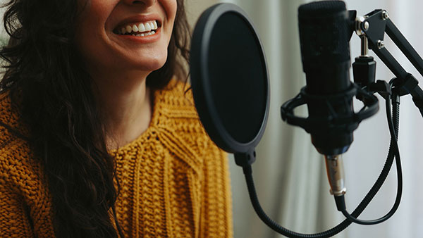 a woman in a yellow sweater speaking into a microphone